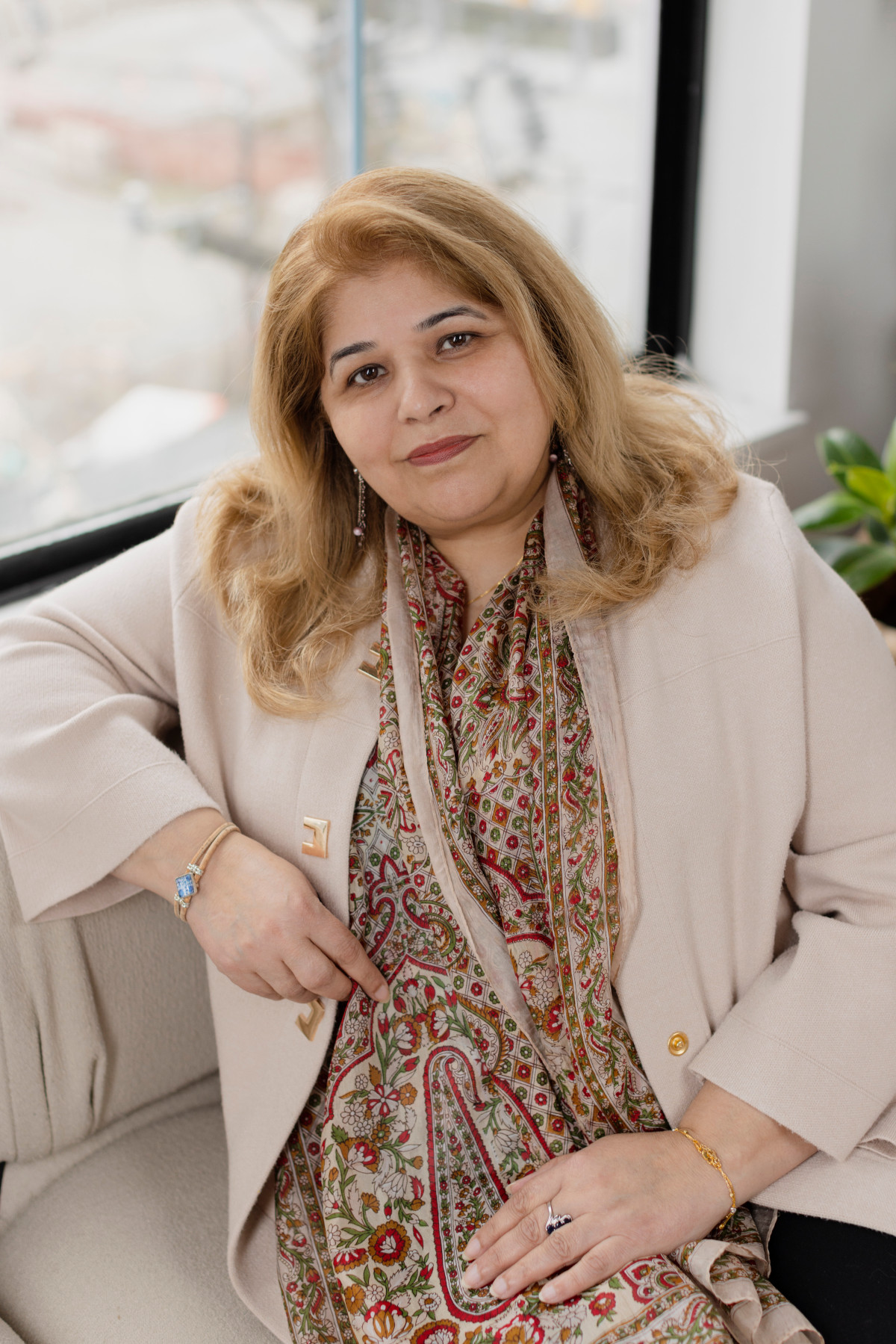 Sangeeta Sirohi headshot. Sitting on couch smiling