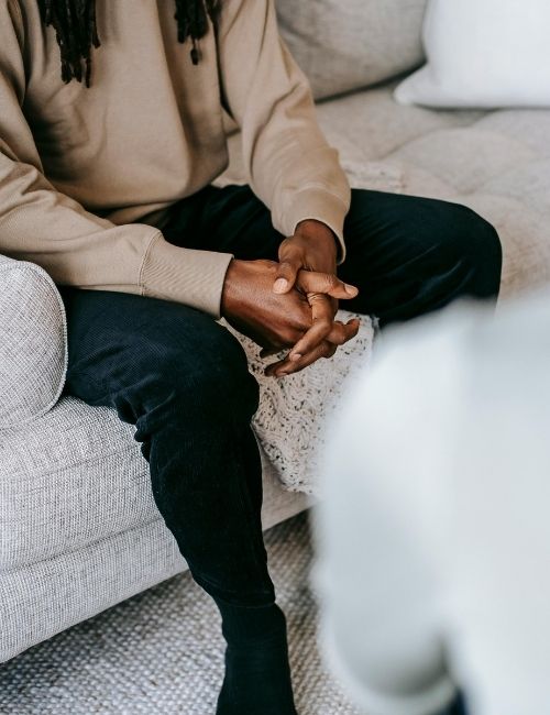 Close up of young man at counselling with hands in his lap