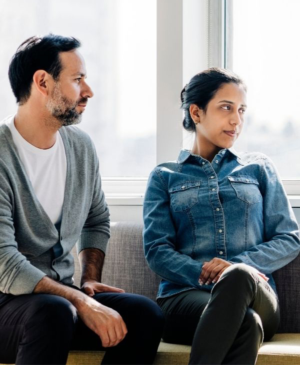 Middle-aged couple sitting in a therapy office together looking at the therapist (not picutred)