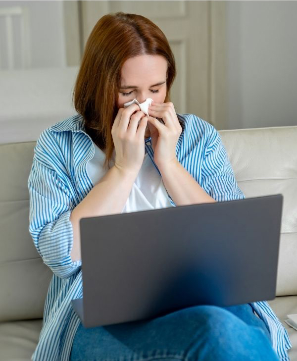 Woman crying with laptop on her lap and wiping her nose with a tissue